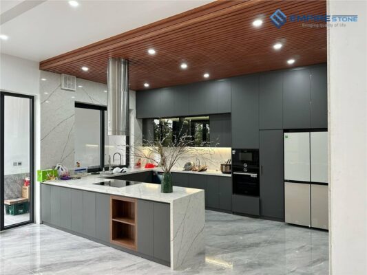 Bếp chữ U tủ xám đậm, mặt đá trắng vân xám và trần gỗ ốp lam