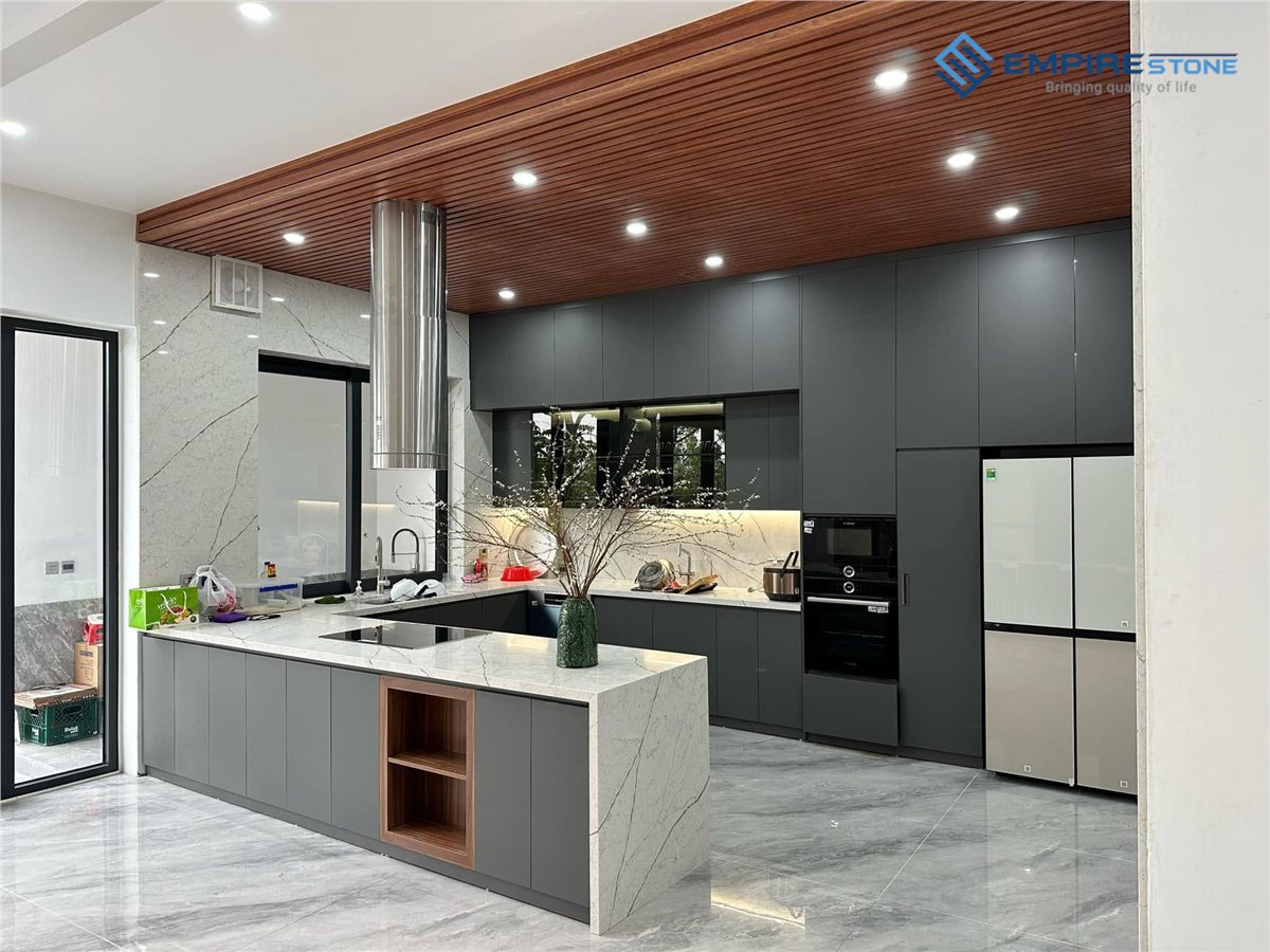 Bếp chữ U tủ xám đậm, mặt đá trắng vân xám và trần gỗ ốp lam